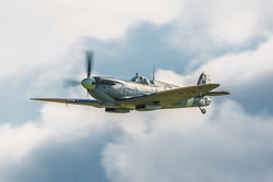 RAF Spitfire fighter flying in a cloudy blue sky
